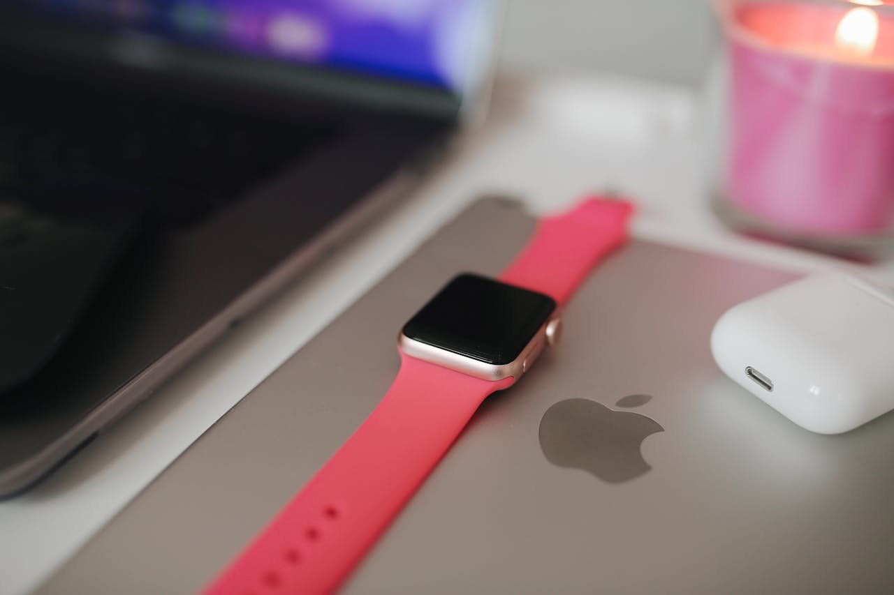 Smartwatch on a laptop with a pink candle setting, showcasing a modern workspace.